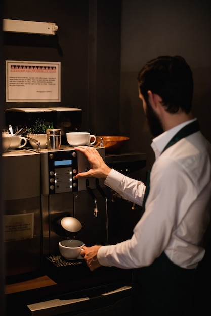 Waiter making cup of coffee from espresso machine