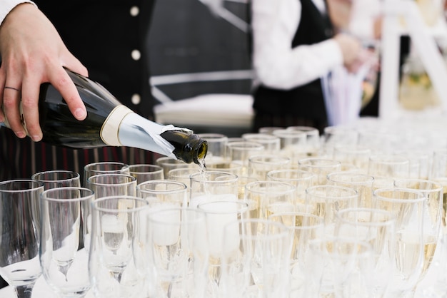 Free photo waiter pouring champagne into glasses