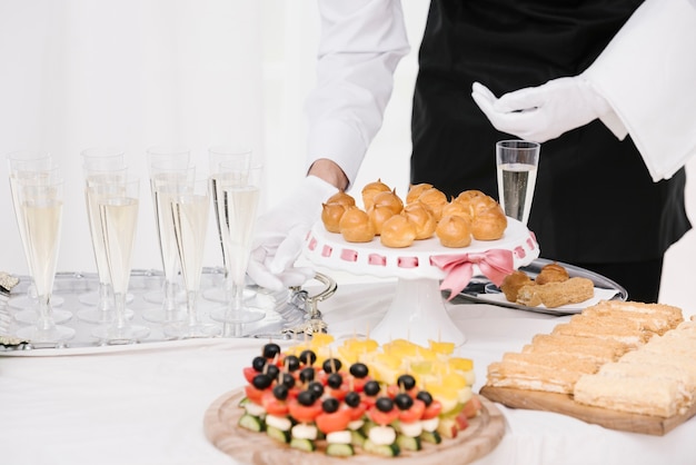 Waiter presenting mix of food and drinks on a table