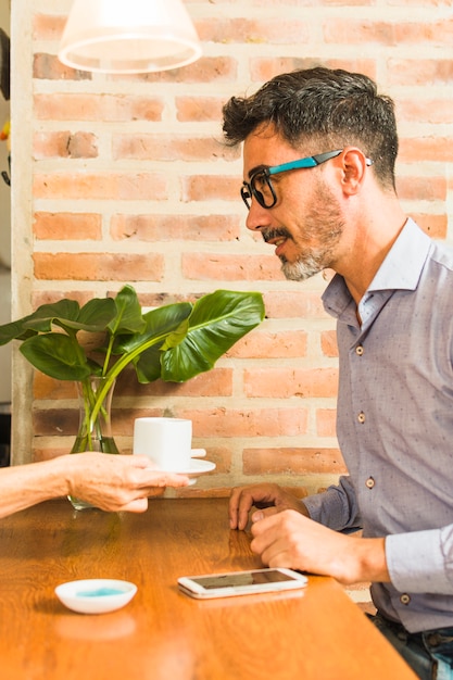 A waiter serving coffee to man sitting at table