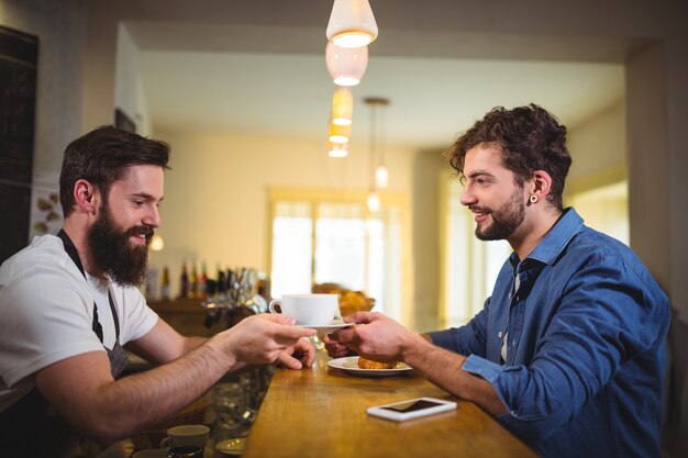 Waiter serving a cup of coffee to customer