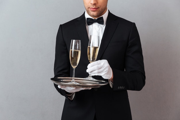 Waiter standing isolated over grey wall