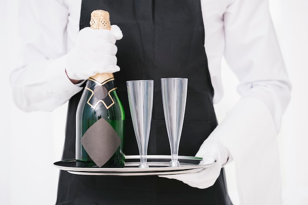 Free photo waiter in uniform holding bottle with glasses