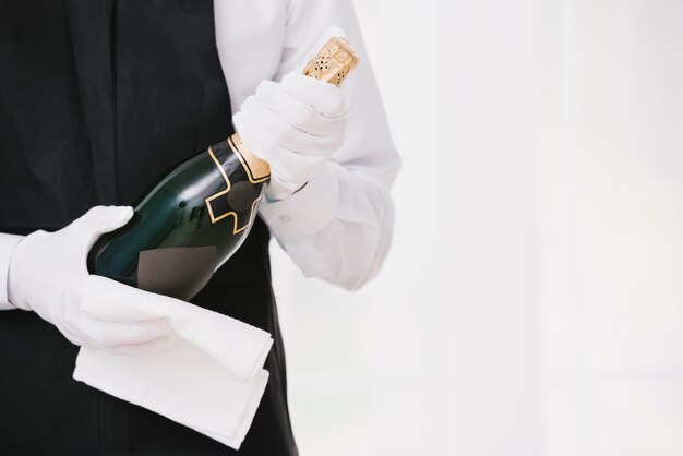 Официант в форме, представляя шампанское