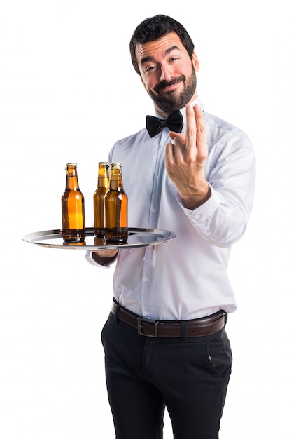 Waiter with beer bottles on the tray coming gesture