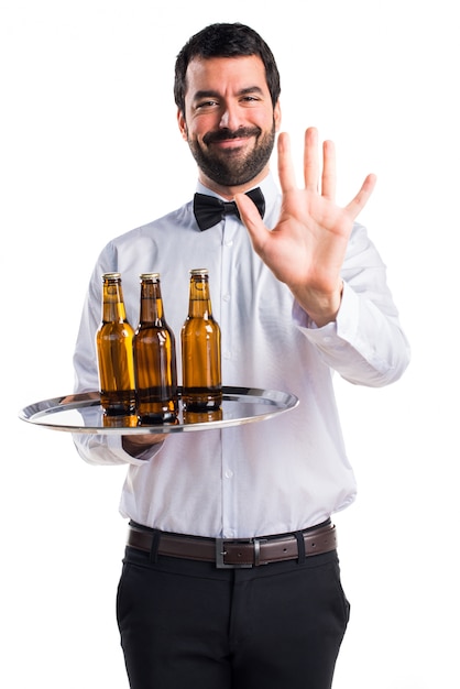 Waiter with beer bottles on the tray counting five