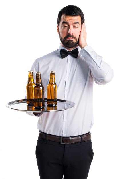 Waiter with beer bottles on the tray covering his ears