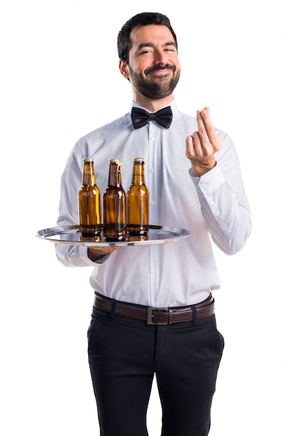 Waiter with beer bottles on the tray doing a money gesture