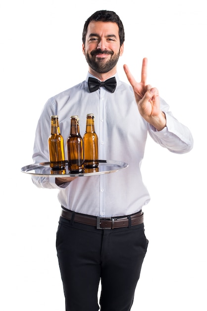 Waiter with beer bottles on the tray doing victory gesture