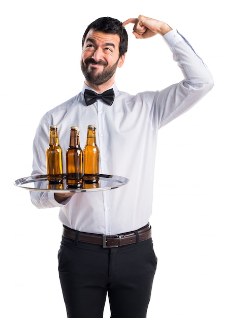 Waiter with beer bottles on the tray having doubts