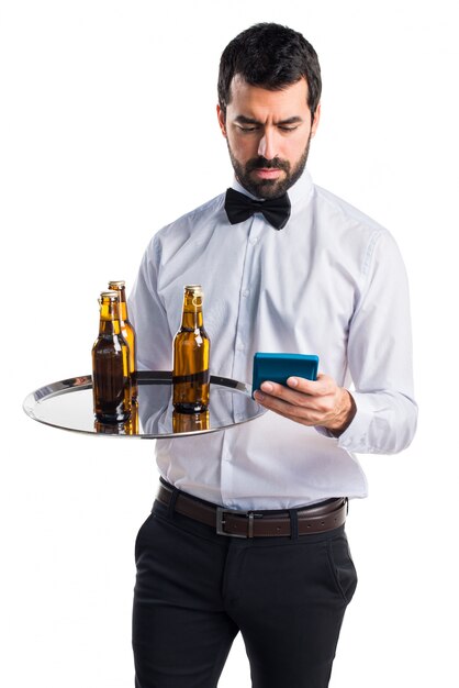 Waiter with beer bottles on the tray holding a calculator