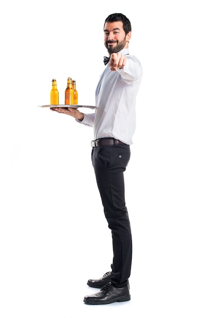 Waiter with beer bottles on the tray pointing to the front