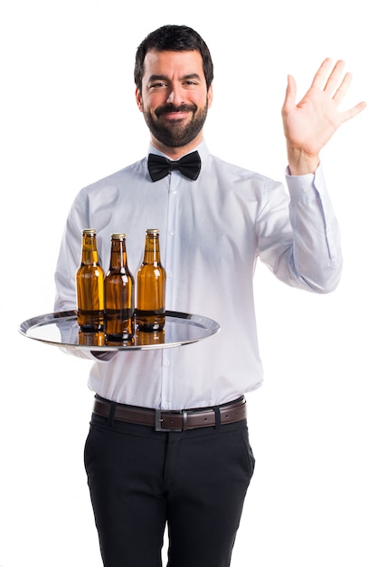 Waiter with beer bottles on the tray saluting