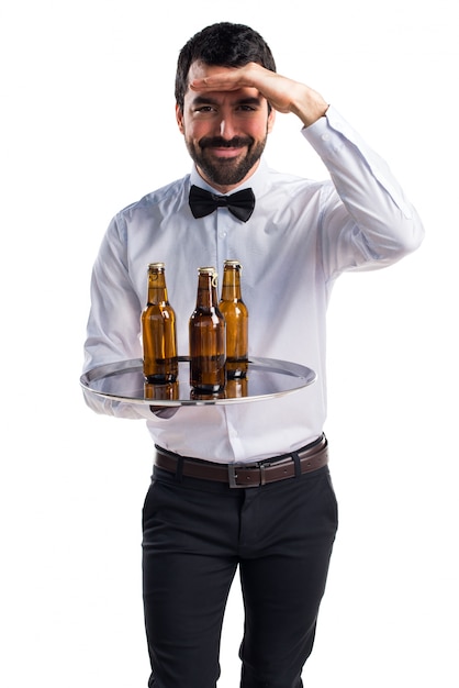 Free photo waiter with beer bottles on the tray showing something