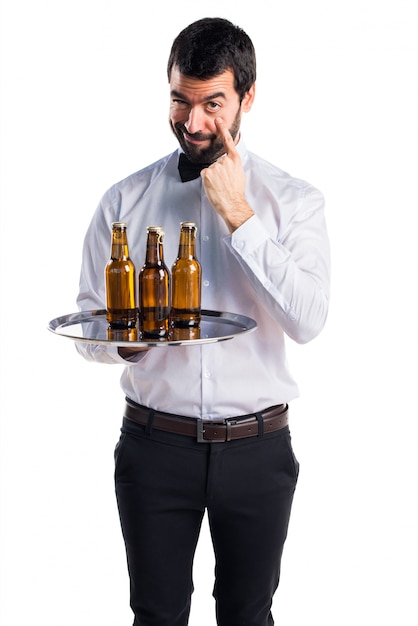 Waiter with beer bottles on the tray showing something