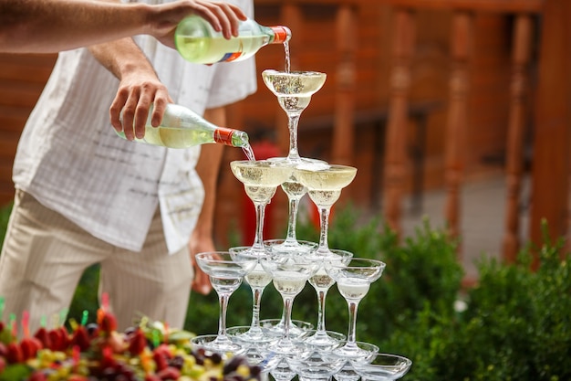 Foto gratuita i camerieri versano champagne su una piramide di bicchieri da vino