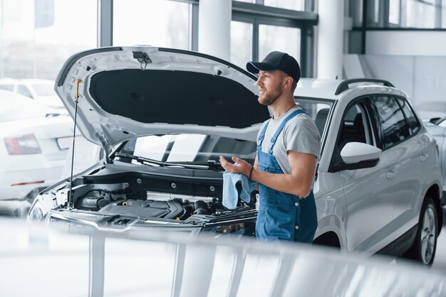 Waiting for the customer. Employee in the blue colored uniform stands in the automobile salon