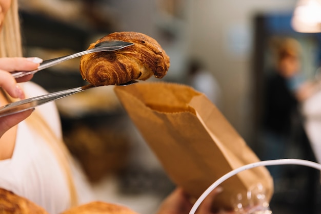 Cameriera che riempie la borsa del croissant