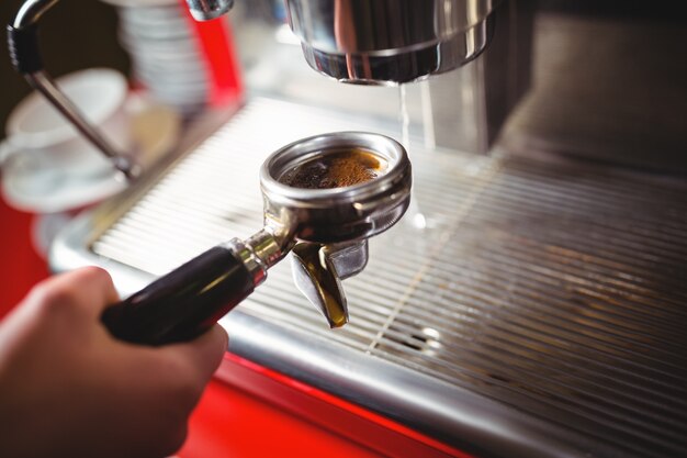 Waitress holding portafilter filled with ground coffee