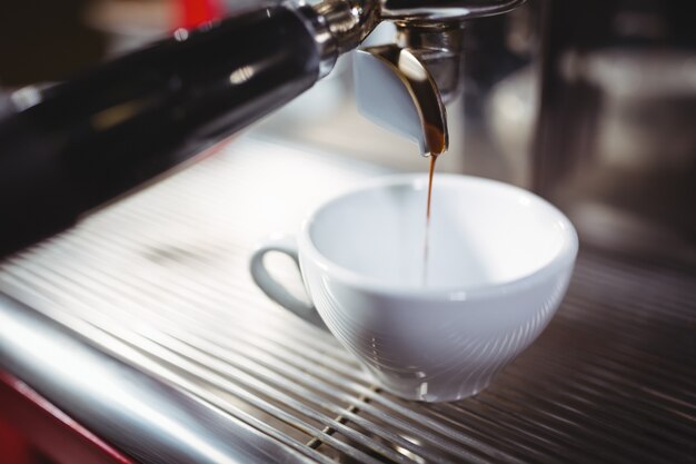 Waitress making cup of coffee at counter in kitchen