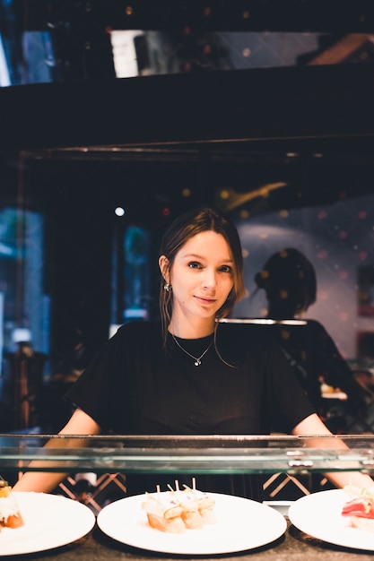 Waitress near display case with tartines