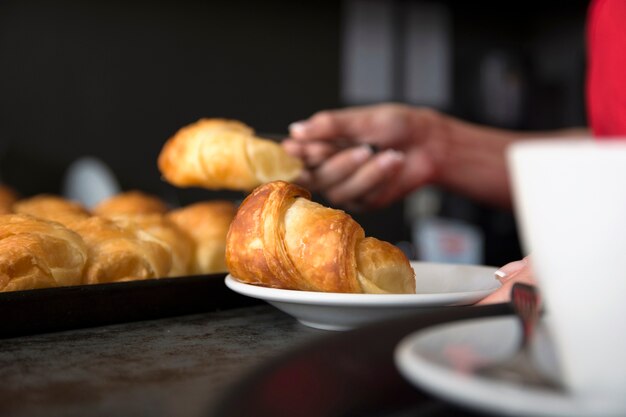 ウェイトレスは、白い​​プレートの焼きたてのクロワッサンを提供