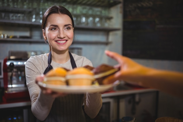Waitress serving a plate of cupcake to customer