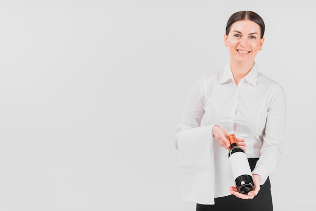 Foto gratuita donna di cameriera che offre una bottiglia di vino