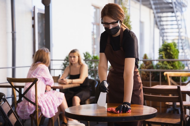 ウェイトレスは、コロナウイルスのパンデミック時に医療用マスク、手袋のレストランで働いています。