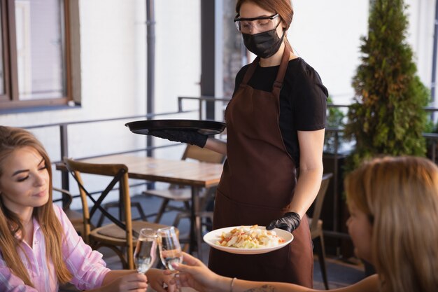 waitress works in a restaurant in a medical mask, gloves during coronavirus pandemic