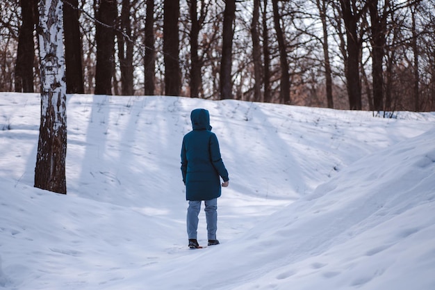 Walk on frosty winter day young caucasian woman in warm clothes stand on snowcovered road in forest ...