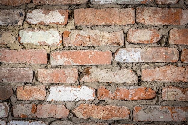 Wall of an old brick building with peeled plaster and painted texture background