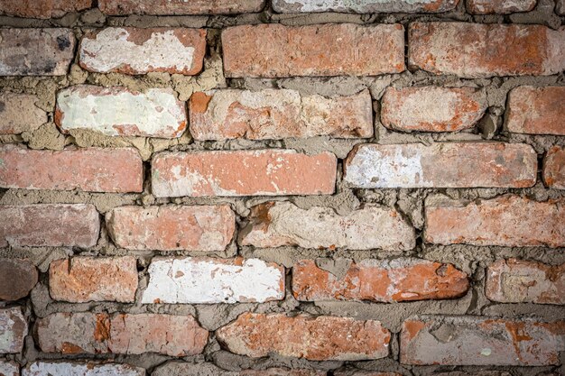 벗겨진 석고와 페인트 질감 배경이 있는 오래된 벽돌 건물의 벽