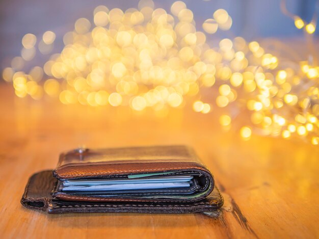 Wallet and mobile cover leather on wooden table with small decorating light bokeh background