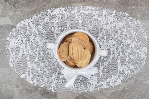호두 모양의 리본이 달린 흰색 그릇에 쿠키. 고품질 사진