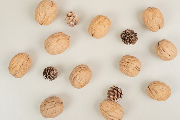 Walnuts and pinecones scattered on beige surface