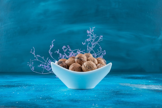 Free photo walnuts in shell in a bowl , on the blue table.