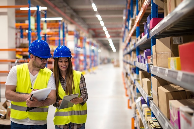 Foto gratuita dipendenti del magazzino che lavorano insieme sul conteggio dei prodotti e sul controllo dell'inventario nel centro di stoccaggio