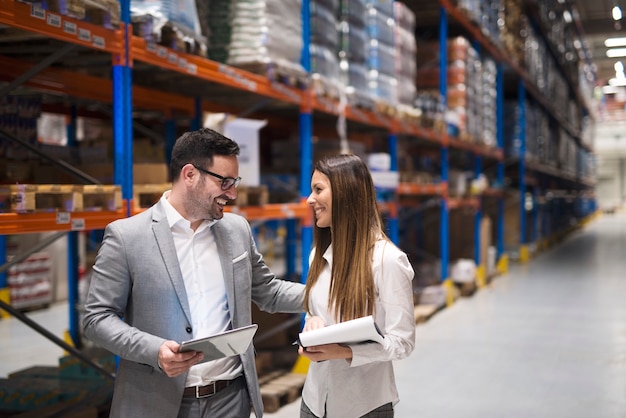 Warehouse managers visiting large warehouse checking distribution