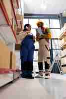 Free photo warehouse operators checking inventory and talking on phone with logistics manager african american factory storehouse workers speaking with freight distribution department on landline telephone