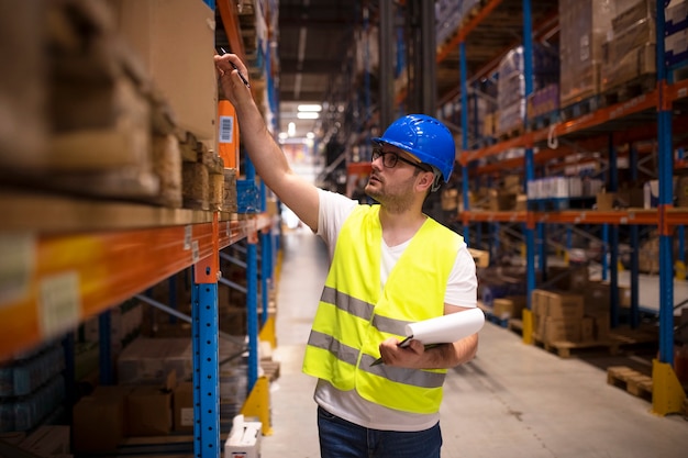 Warehouse worker checking inventory in large distribution warehouse