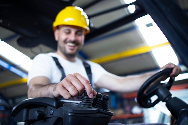 Warehouse worker with yellow hardhat operating forklift machine