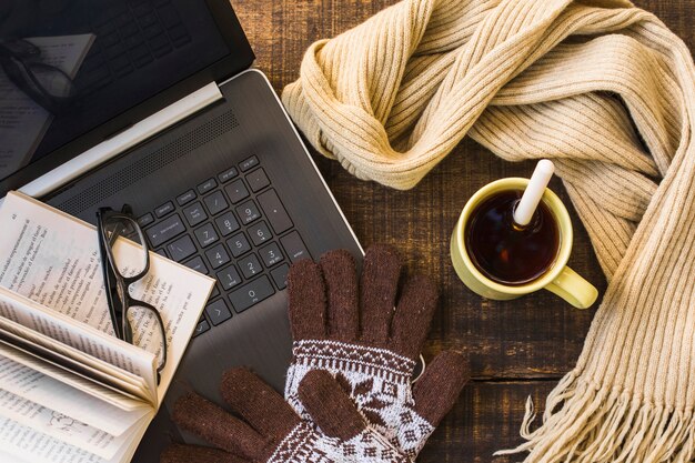 Warm clothing and hot drink near laptop and book