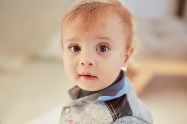 Free photo warm colours. charming little girl stands in a cosy beige room and looks surprised