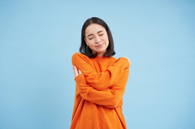 Free photo warmth and tenderness cute korean girl hugs herself embrace equite femenism and international womens
