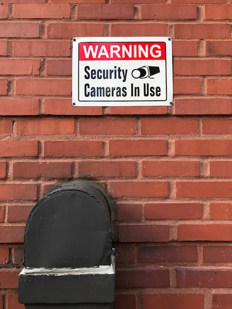 Free photo warning security cameras in use sign on a brick wall