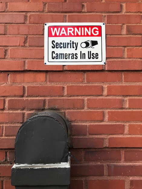 Warning security cameras in use sign on a brick wall