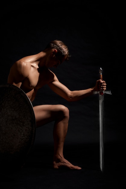 Воин с мечом стоит на коленях.