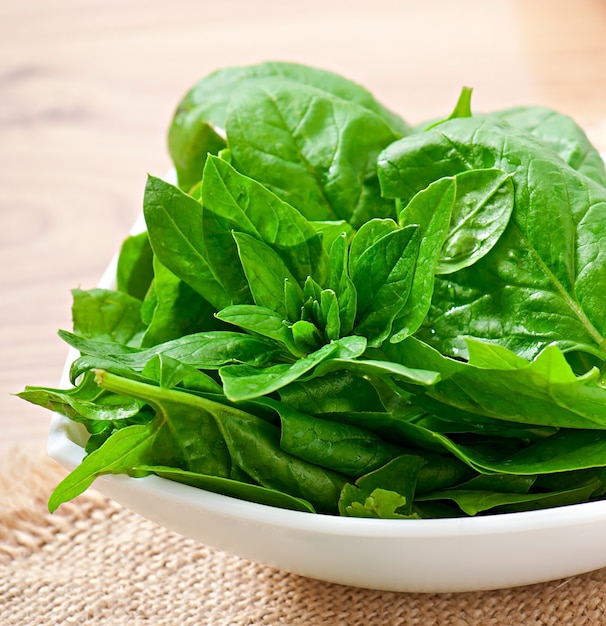 Washed spinach leaves in a bowl on a wooden table