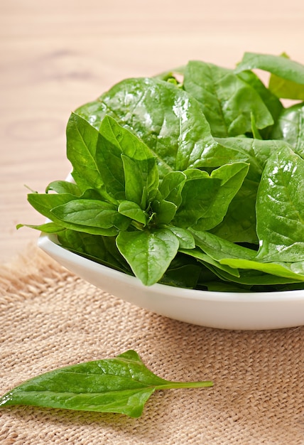 Washed spinach leaves in a bowl on a wooden table